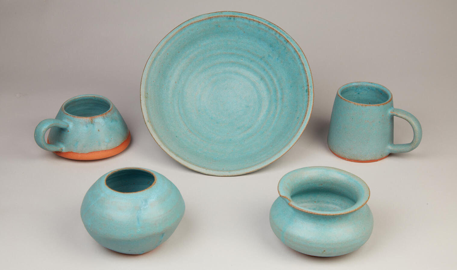 "Turquoise Form and Function," 2021. Wheel-thrown, turquoise-glazed, red clay, wheel-thrown mugs, vases, and serving bowl, various sizes, $40 each.
